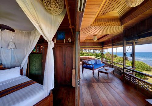 a bedroom with a bed and a balcony with the ocean at Jasri Bay Hideaway in Jasri