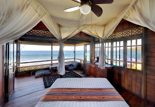a bedroom with a bed with a view of the ocean at Jasri Bay Hideaway in Jasri