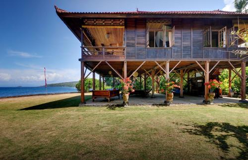 a house with a bench in front of the ocean at Jasri Bay Hideaway in Jasri
