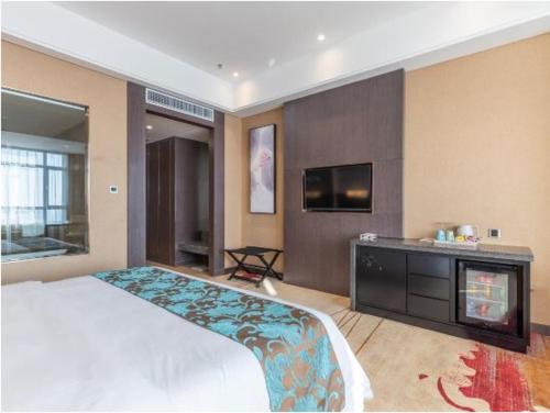 a bedroom with a bed and a flat screen tv at Shenyang Huaqiang Novlion Hotel in Daoyi