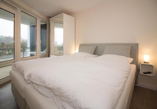 sypialnia z dużym białym łóżkiem i oknami w obiekcie Kurpark-Residenz W112 w mieście Cuxhaven