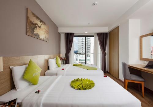 Una habitación de hotel con dos camas y un escritorio. en Ale Nha Trang Hotel, en Nha Trang