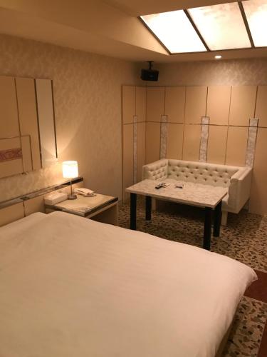 Cette chambre comprend deux lits, une table et un canapé. dans l'établissement Prime Hotel Fulula プライムホテル フルーラ, à Osaka
