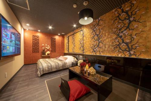 1 dormitorio con 1 cama y una pared con una pintura en Hotel Waraku Shibukawa, en Shibukawa