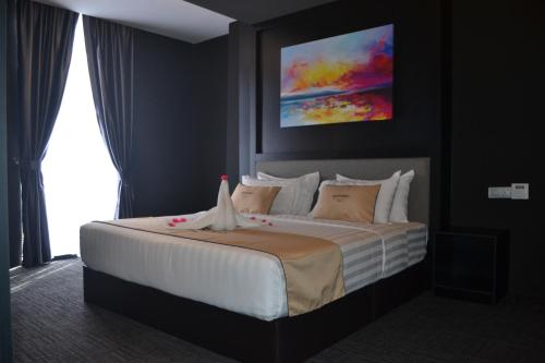 a bedroom with a bed with a painting on the wall at Artworks Hotel Ipoh in Ipoh