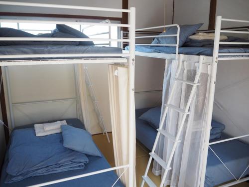 two bunk beds in a room with blue pillows at Guesthouse ＆ Beach Cafe Fuego in Hyuga