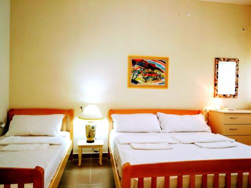 a bedroom with two beds and a table with a lamp at Turtle Apartment in Durrës