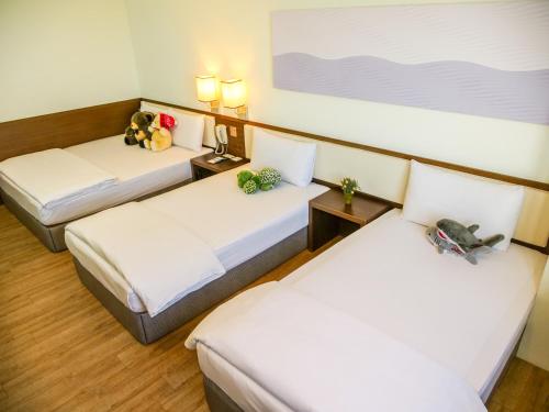 two beds in a hotel room with stuffed animals on them at MF Hotel, penghu in Magong