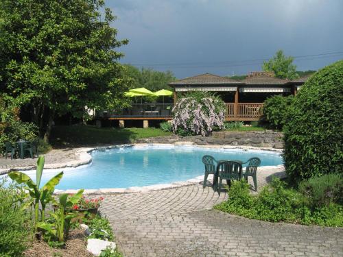 una piscina con sillas y una mesa en un patio en Au Faisan Doré, en Neuville-sur-Ain