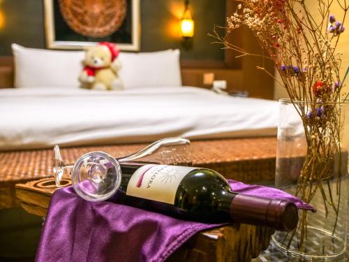 a bottle of wine on a table next to a bed at MF Hotel, penghu in Magong