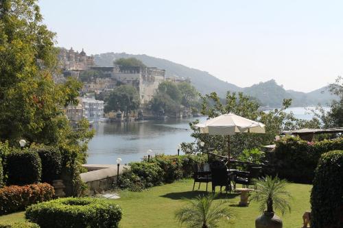 a view of a river with chairs and an umbrella at Karohi Haveli - A Heritage Hotel in Udaipur