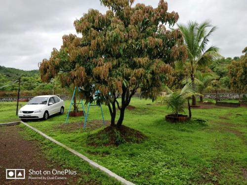 a white car parked next to a tree at Shree Samarth Farmhouse in Murud