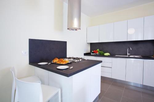 a kitchen with white cabinets and a black counter top at Residence Sala Comacina apartment no 2 with pool and spa by Italian Apartments in Isola Comacina