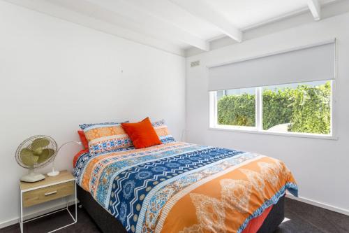a white bedroom with a bed and a window at At Agnes Ave: coastal views in Blairgowrie