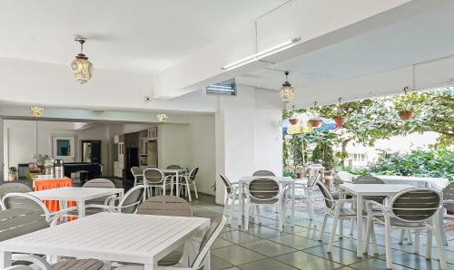 a restaurant with white tables and chairs in a room at Treebo Brooks Manor in Pune