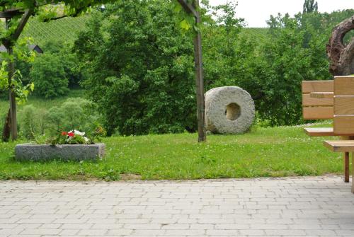 a park with a bench and a rock structure in the grass at Weingut Primus Südsteiermark in Spielfeld