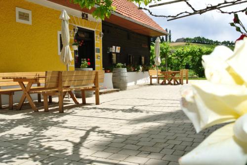 a patio with benches and umbrellas in front of a building at Weingut Primus Südsteiermark in Spielfeld