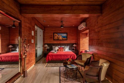 a bedroom with wooden walls and a bed with red sheets at Salcete Beach Resort in Colva