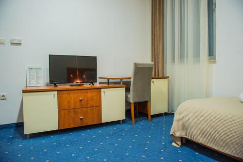 um quarto de hotel com uma televisão e uma secretária com uma cama em Hotel CITY em Prnjavor