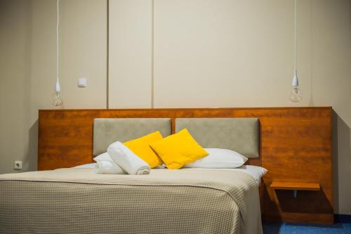a bed with yellow and white pillows on it at Hotel CITY in Prnjavor