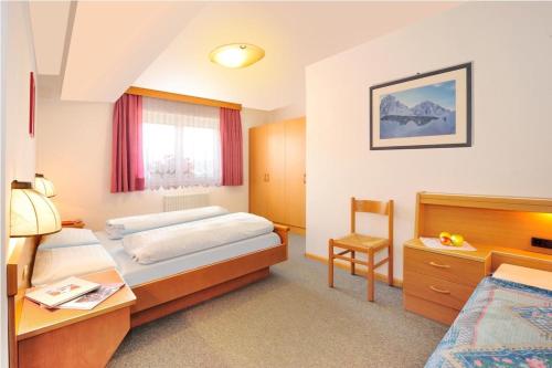 a hotel room with two beds and a desk at Apartments La Baita in Santa Cristina Gherdëina