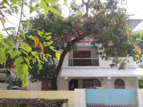 a white house with a tree in front of it at Casa Feliz in Fort Kochi