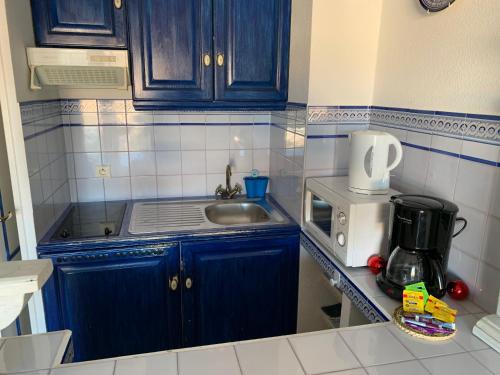 - une cuisine avec des placards bleus, un évier et une cafetière dans l'établissement Port Grimaud Les Voiles, à Grimaud