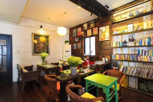 a restaurant with tables and chairs and bookshelves at Hofang Guest House in Hangzhou