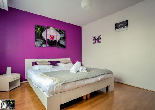 a bedroom with a bed with a purple wall at Appartement Spacieux Schiltigheim in Schiltigheim