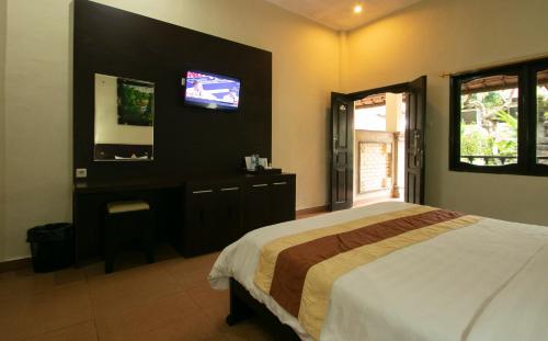 a bedroom with a bed and a tv on the wall at Bali Sandy Resort in Kuta