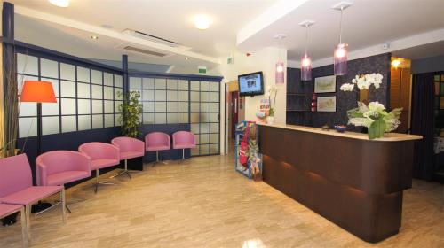 a waiting room with pink chairs and a counter at Hotel Loretta & Dependance in Cervia