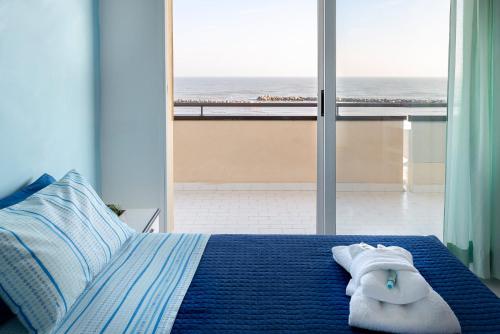 um quarto com uma cama azul e vista para o oceano em Residence Belvedere Vista em Rimini