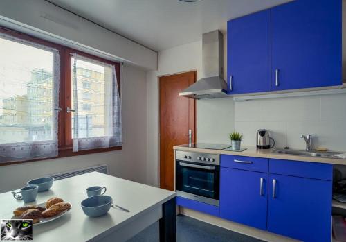 une cuisine avec des placards bleus et une table avec du pain dans l'établissement Appartement Spacieux Schiltigheim, à Schiltigheim