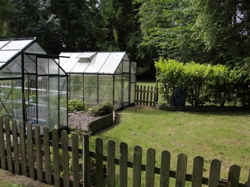 two greenhouses in a garden behind a fence at Apartment in Quend near the Sea in Quend
