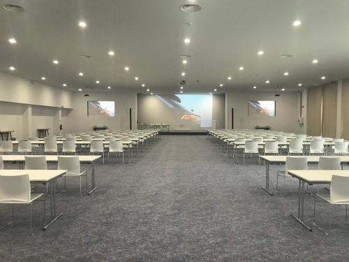 a large room with rows of tables and white chairs at MH Atlantico in Peniche