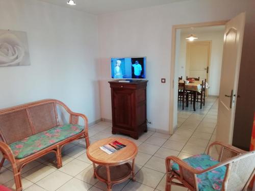a living room with chairs and a tv and a table at Holiday home with swimming pool in Quend