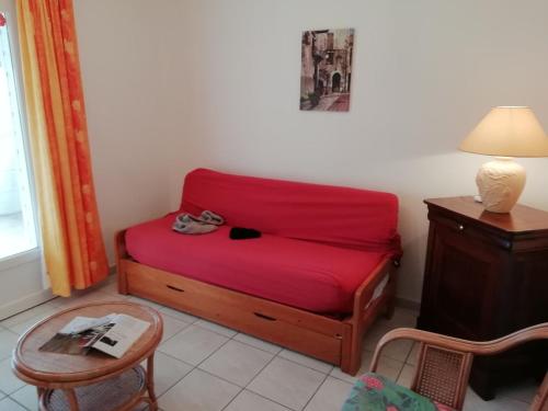 a small red bed in a room with a table at Holiday home with swimming pool in Quend