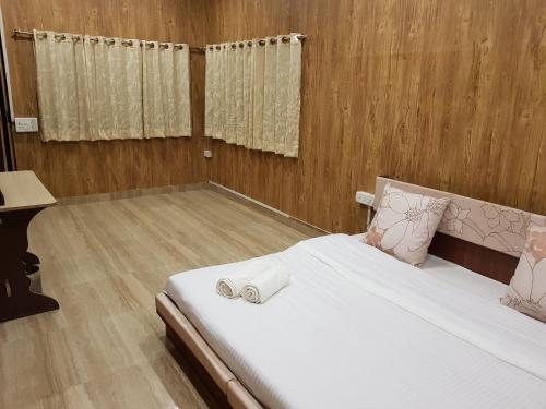 a bedroom with a bed with white sheets and wooden walls at Living Green Farms in Allahābād