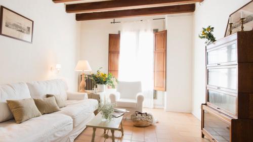 a white living room with a white couch and a table at Mas del Mar in Sant Pere Pescador