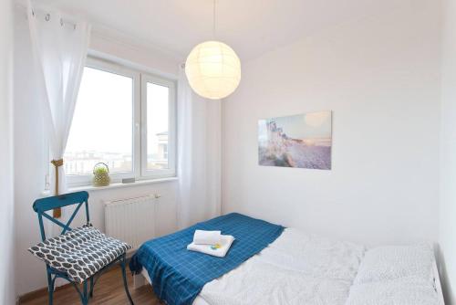 a bedroom with a bed and a chair and a window at Apartament Zaciszny in Gdańsk