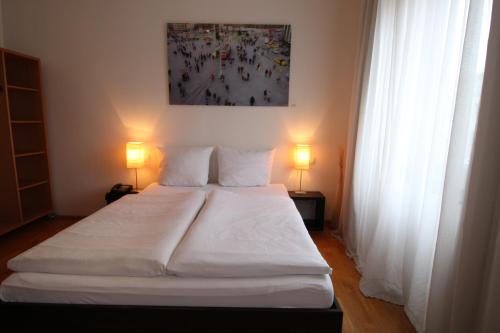 a bedroom with a large white bed with two lamps at Hotel Lorenz in Essen