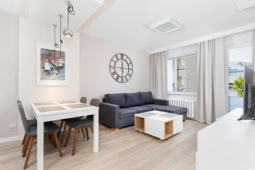 a living room with a blue couch and a table at Premium apartment with a port view by Renters in Świnoujście