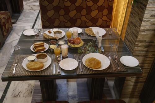 a table with plates of food and glasses of orange juice at Hotel Agra Dazzling East Gate in Agra