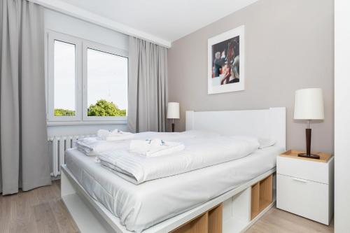 a white bedroom with a large bed and a window at Premium apartment with a port view by Renters in Świnoujście
