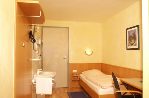 a small room with a bed and a sink at Berg-Cafe in Kempten
