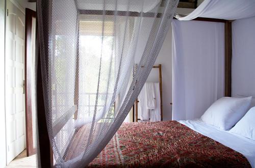 a bedroom with a canopy bed and a window at Estalagem Camburi in Camburi