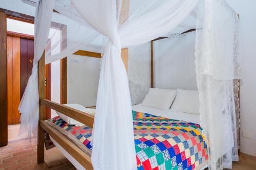 a bedroom with a bed with a canopy at Estalagem Camburi in Camburi