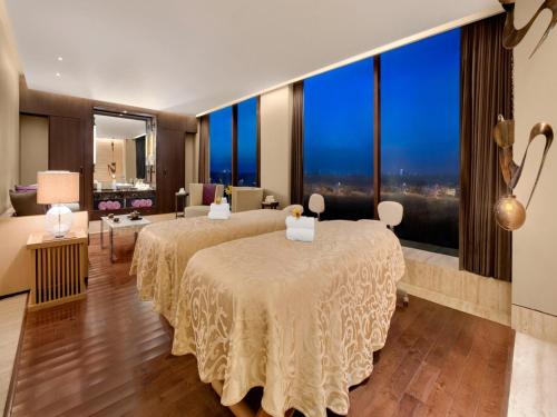 two beds in a hotel room with large windows at The Leela Ambience Convention Hotel Delhi in New Delhi