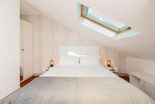 een witte slaapkamer met een bed en een dakraam bij Lisbon Times Apartments in Lissabon