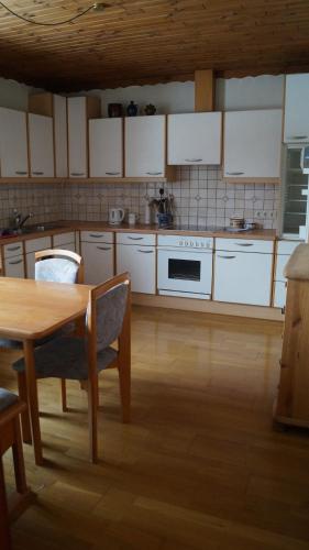 - une cuisine avec des placards blancs, une table et une cuisinière dans l'établissement Ferienwohnung auf einem richtigen Bauernhof, à Finkenstein